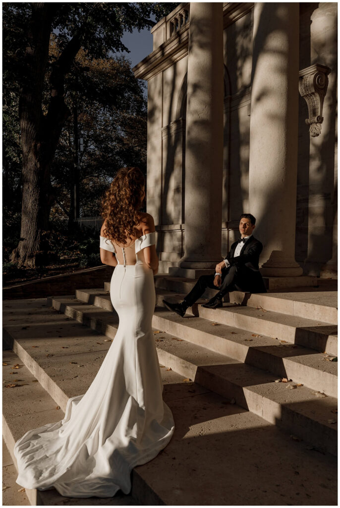 Stylish couple on their wedding day sitting on the steps of the Rodin Museum in Philadelphia while the sun sets and casts a dramatic light on them